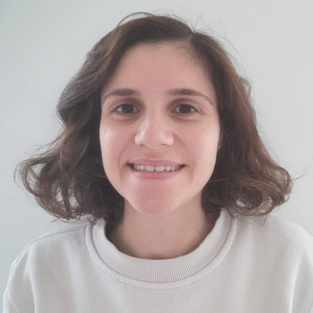 Picture of a women with long dark hair and a white top.
