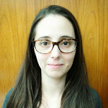 Foto einer Frau mit langen dunklen Haaren und einer Brille.