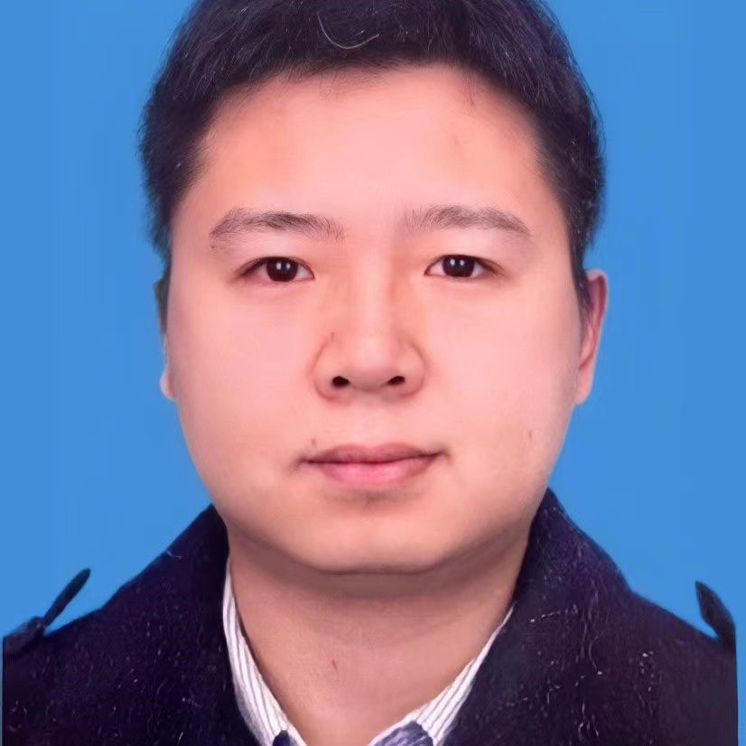 Picture of a man with dark hair in front of a blue background.