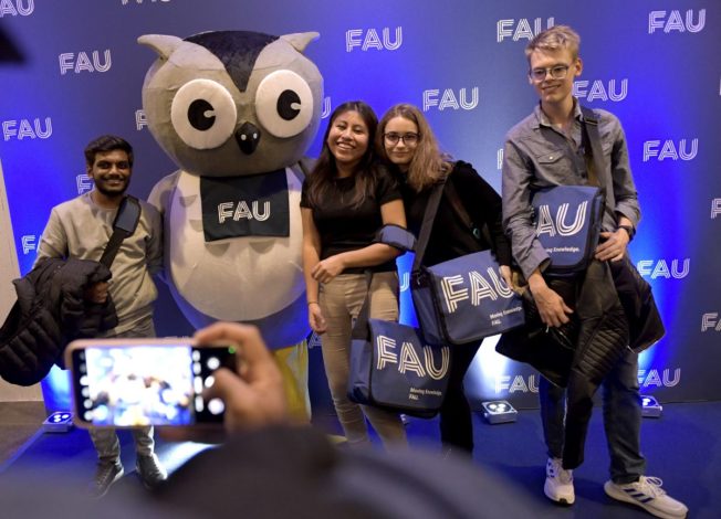 Studierende mit Erstsemestertaschen und FAU-Eulen-Maskottchen