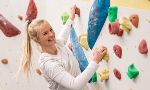 Frau lächelnd an Boulderwand