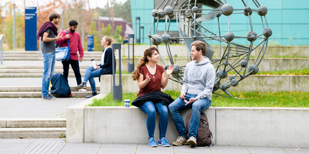 Studierende sitzen vor dem Chemikum-Gebäude