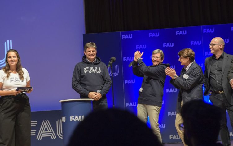 Universitätsleitung auf dem Podium in der Heinrich-Lades-Halle bei der Erstsemesterbegrüßung am Apllaudieren