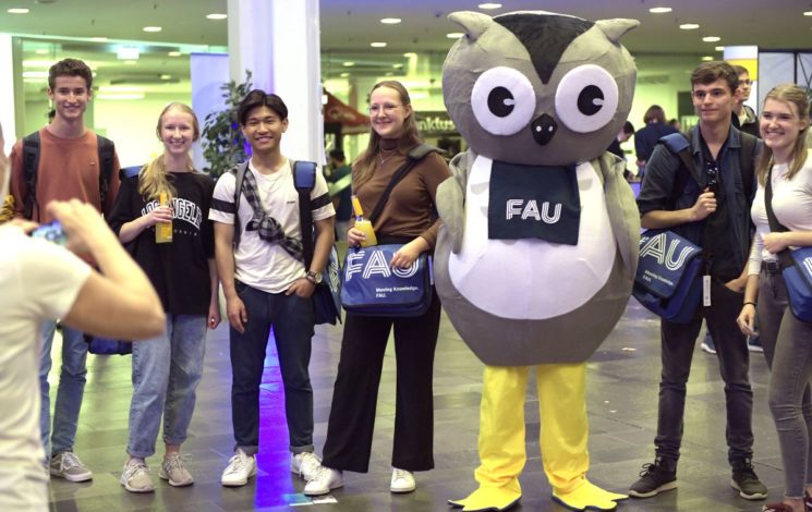 Studierende mit Erstsemestertaschen und FAU-Eulen-Maskottchen