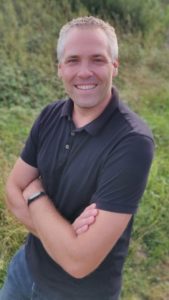 A man with gray hair wearing a dark polo shirt