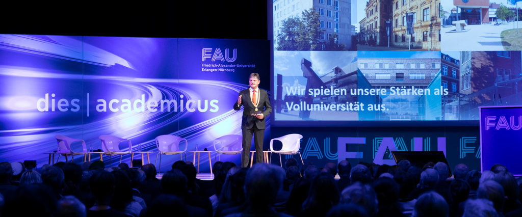 A man in a suit is standing on a stage giving a speech.