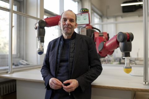 Porträt eines Mannes im Labor mit Roboter im Hintergrund