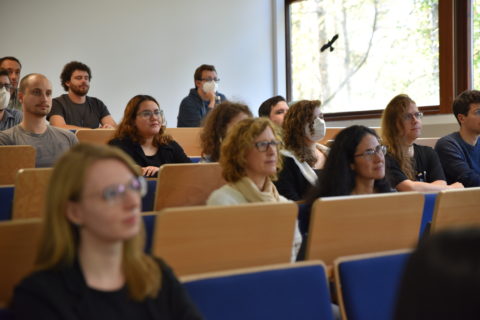 Personen sitzen in einem Vorlesungsraum und schauen nach vorne.