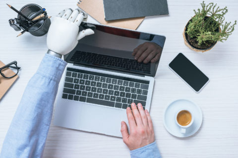 Ein Mensch mit einer Handprothese klappt einen Laptop auf.