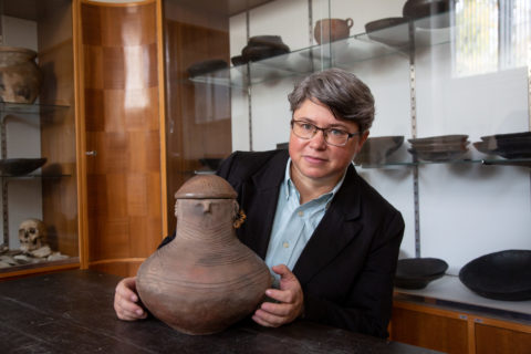 Frau mit altem Tongefäß in der Hand.