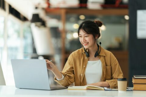 Studentin an Laptop vor Büchern und Kaffee an Tisch