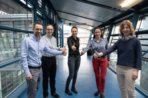 Gruppenbild mit drei Frauen und zwei Männern in einem Klinik Gang. Die fünf Personen halten die Daumen hoch.