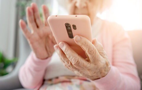 Seniorin tippt auf einem Smartphone.