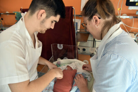 Ein Pfleger und eine Pflegerin versorgen ein Neugeborenes.