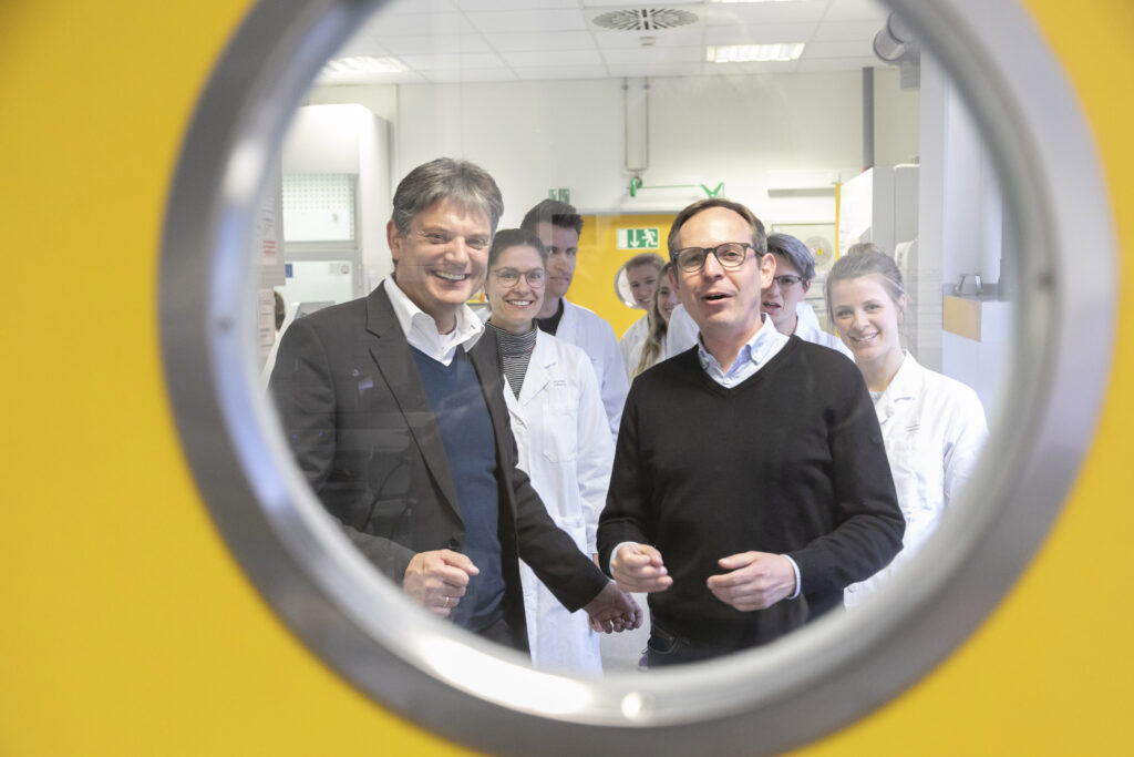 Prof. Dr. Veith Rothhammer and his team look through the lab door together with Prof. Dr. Joachim Hornegger.