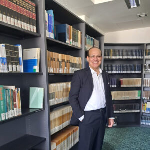 Ein Mann steht vor Bücherregalen.