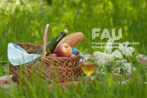 Picknickkorb in grünem Graß mit FAU-Logo