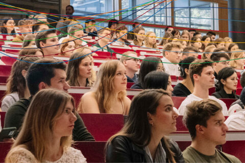 In einem Hörsaal der WiSo in Nürnberg sitzen viele junge Menschen. Alle blicken nacht rechts. Die Köpfe sind nach rechts gedreht.