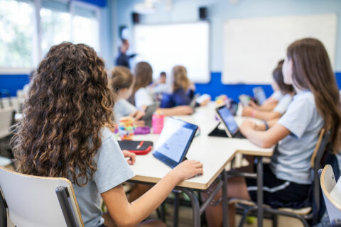 Schülerinnen und Schüler mit Tablets in einem Klassenzimmer.