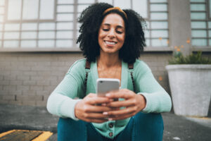 Smartphone, chat and black woman on campus street for outdoor 5g communication, social network update or scroll university website information. College student using phone social media or job search