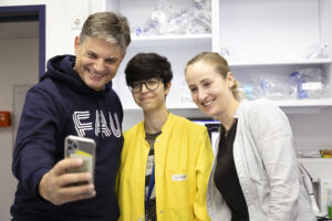 Ein Mann macht ein Selfie zusammen mit einem anderen Mann und einer Frau in einem Labor.