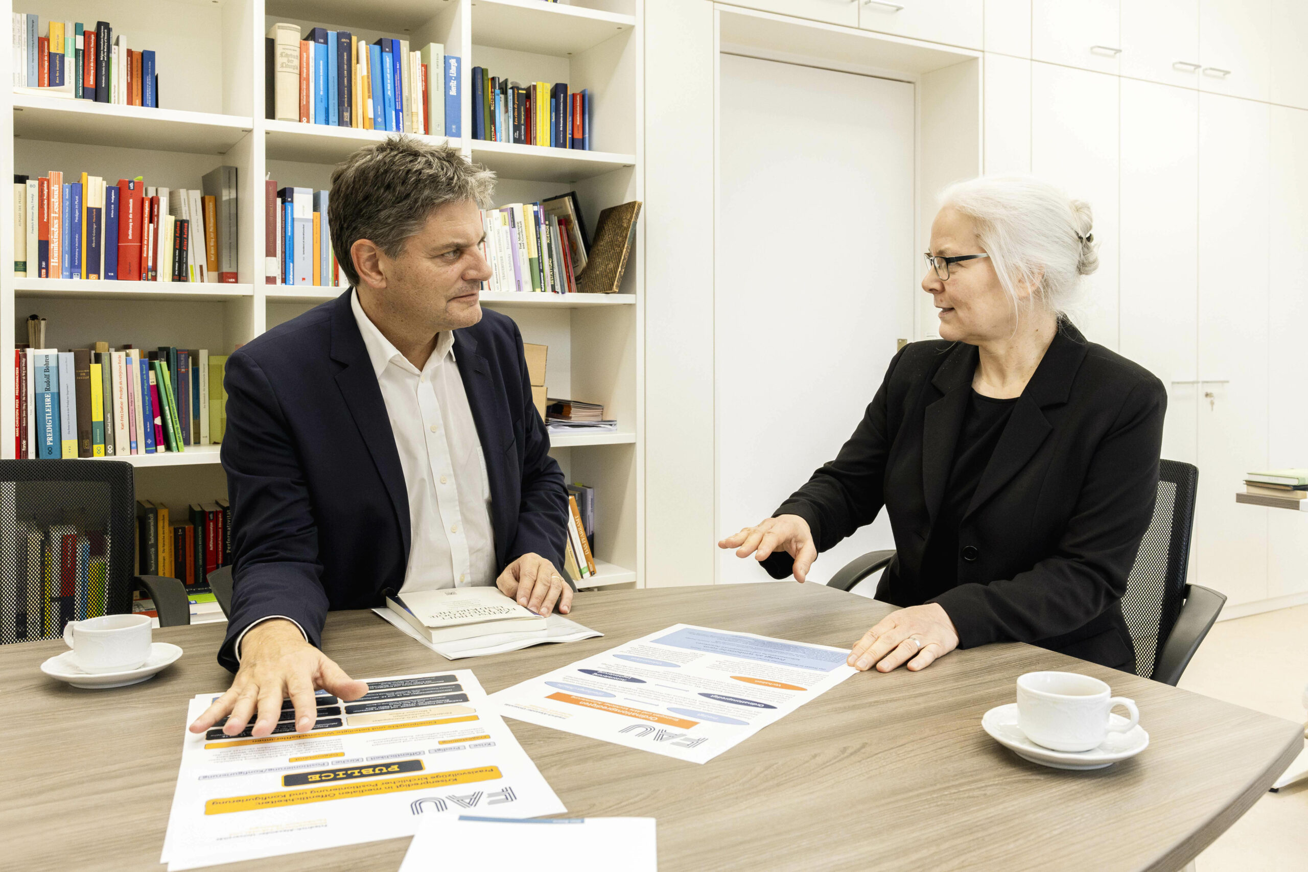 Eine Frau und ein Mann sitzen an einem Tisch und unterhalten sich. 