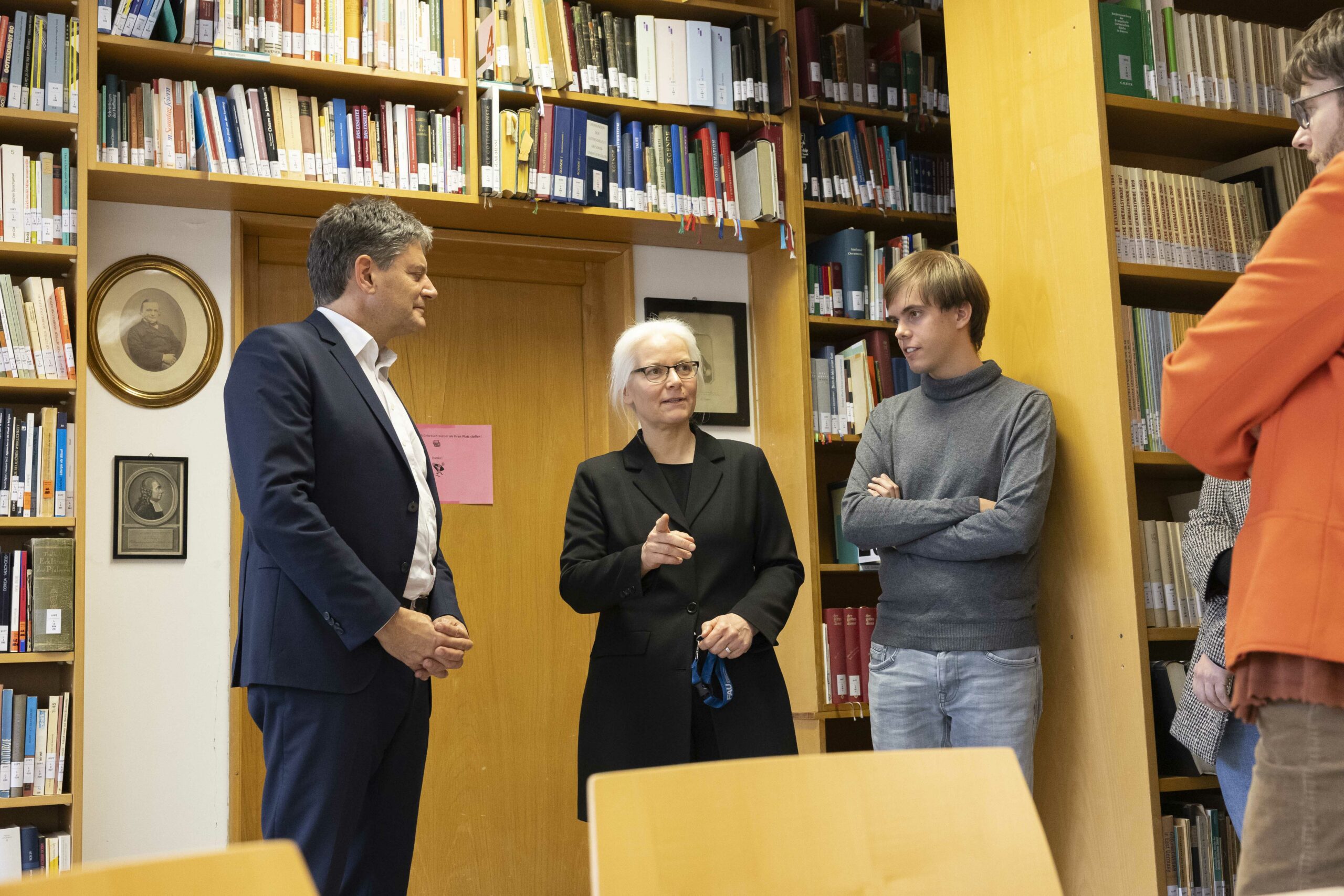 Eine Gruppe Personen unterhält sich in einer Bibliothek. 