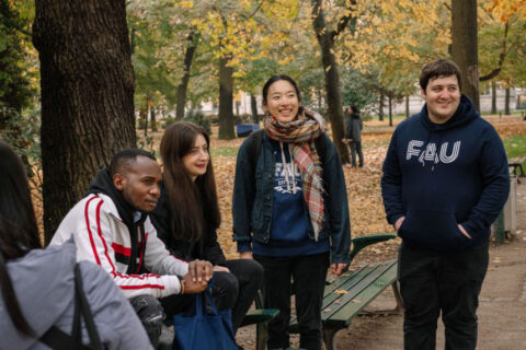 diverse Studierende der Friedrich-Alexander-Universität Erlangen-Nürnberg auf einer Bank im Schlossgarten