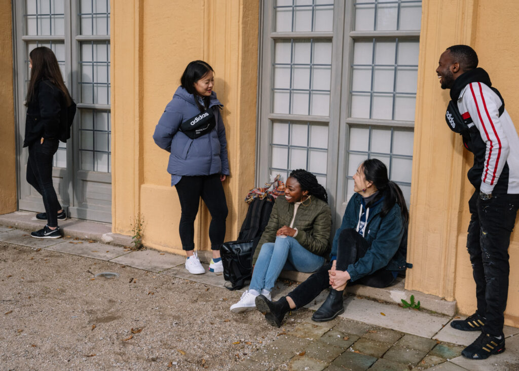 Studierende sitzen vor Erlanger Orangerie im Schlossgarten der FAU