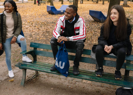 Die FAU ist ein Ort der Begegnung. Studierende aus der ganzen Welt sind Teil der FAU-Community. Hier sitzen Studiernde gemeinsam auf einer Parkbank im Erlanger Schlossgarten. (FAU/Anna Tiessen)