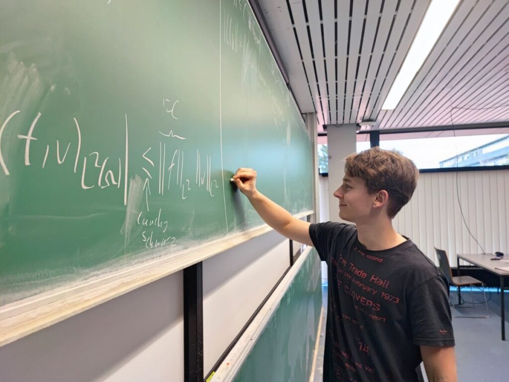 Tutor Jonathan Lang schreibt an eine Tafel