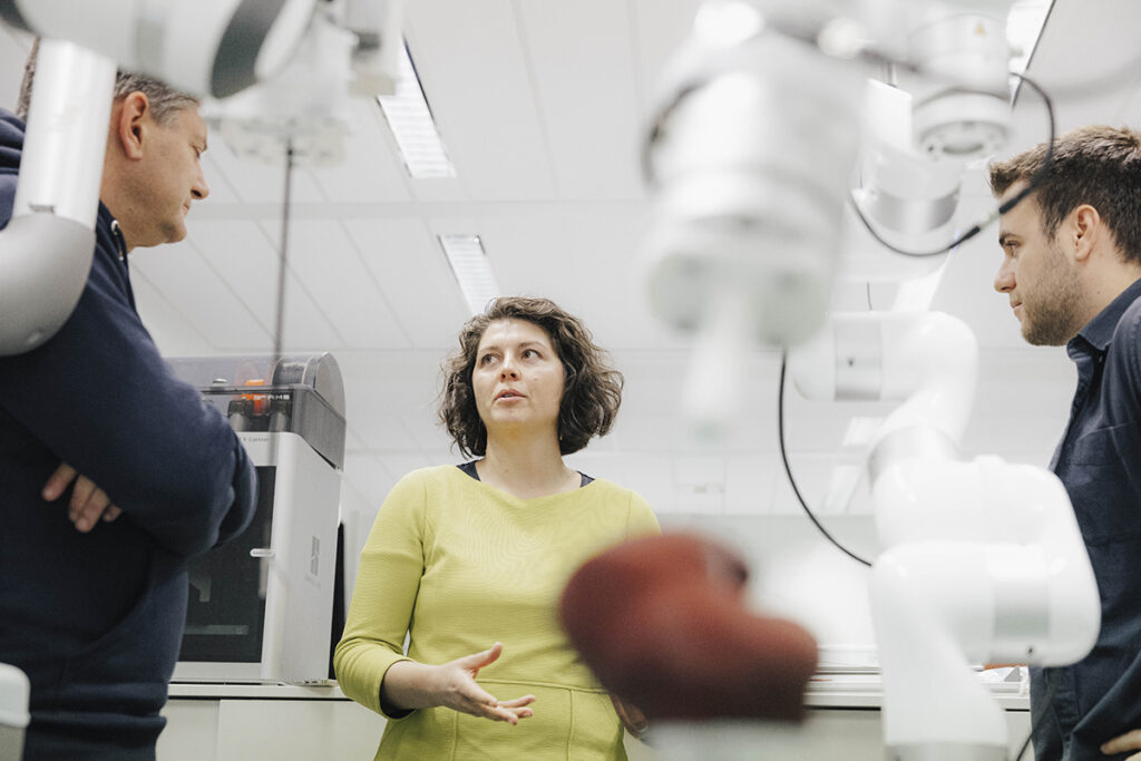 Prof. Mathis-Ullrich is explaining something. A robotic arm can be seen in the foreground. 