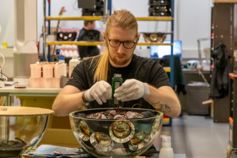 Techniker, der die untere Hemisphäre eines digitalen optischen Moduls (DOM) integriert. Insbesondere geht es um den Anschluss des Photomultiplier Tubes an die Elektronik, die für das Auslesen und die Digitalisierung des erfassten Signals zuständig ist. Bild: Marco Kraan_Nikhef