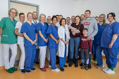 Teamarbeit: 16 Ärztinnen, Ärzte und Pflegefachkräfte der Kinder- und Jugendklinik des Uniklinikums Erlangen versammeln sich um die Eltern des kleinen David, seine Zwillingsschwester Adele und seinen großer Bruder Lev.