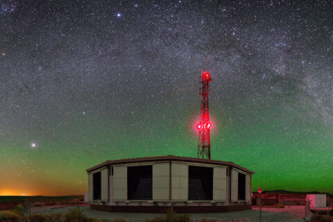 Ein Gebäude des Teleskops bei Nacht. darüber der Sternenhimmel.
