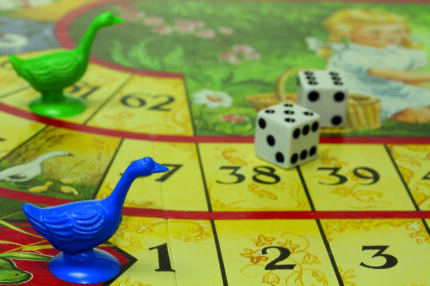 Brettspiel mit Gänsefigur und Würfel