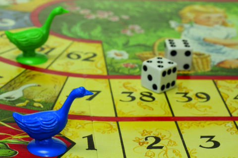 Brettspiel mit Gänsefigur und Würfel
