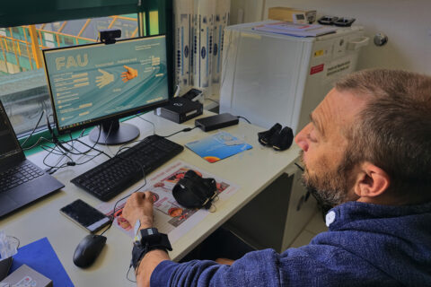Älterer Mann übt mit der seiner Prothese an seinem Arbeitstisch.