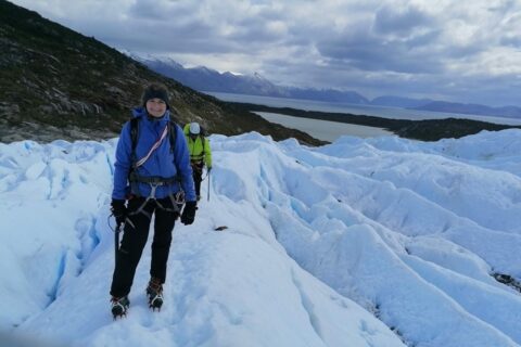 Franziska Temme, eine braunhaarige sportliche Frau in blauem Anorak auf einem Eisfeld. Im Hintergrund ihr Kollege in einem gelben Anorak.