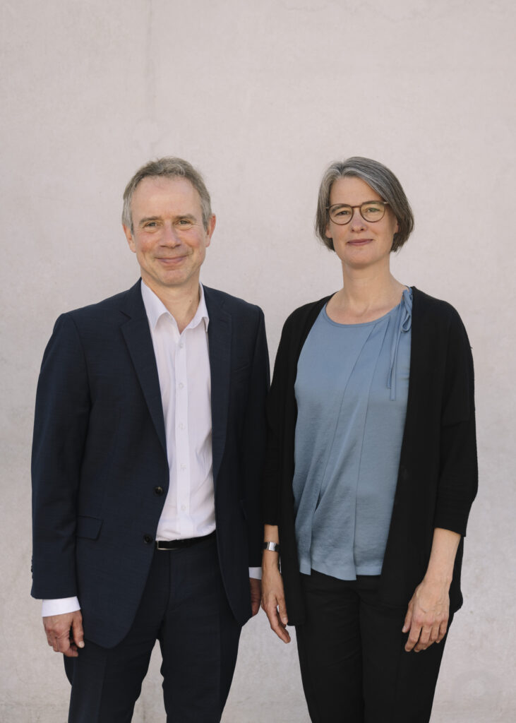 Markus Krajewski, ein Mann mittleren alters, mit grau meliertem Haar und Geheimratsecken, steht neben Katrin Kinzelbach, einer Frau mittleren Alters mit grauen Strähnen und Brille. 