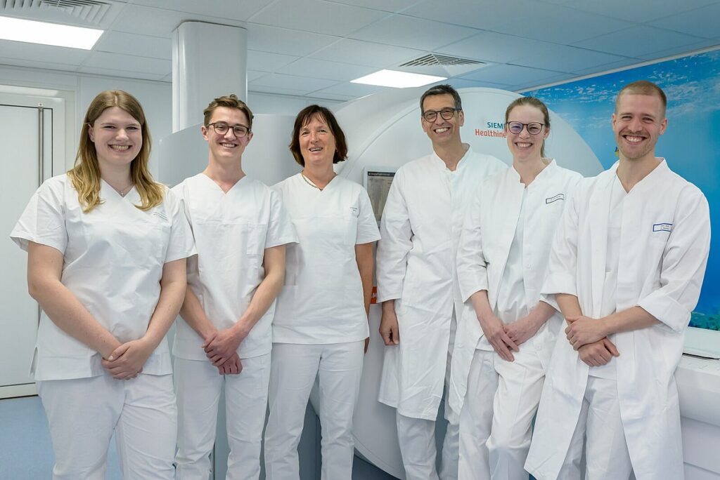 Drei Mitarbeiterinnen und drei Mitarbeiter der Radiologie stehen vor MRT.