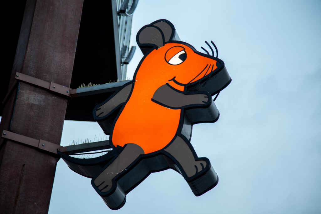Ein Schild mit der Maus aus der Sendung mit der Maus. eine große Zeichtrickmaus.