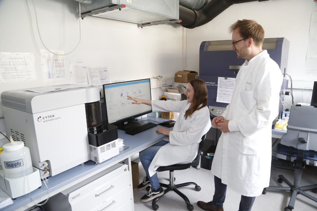 Prof. Schober und eine wissenschaftliche Mitarbeiterin vor einem Computerbildschirm, sie erklärt ihm etwas und deutet auf etwas.
