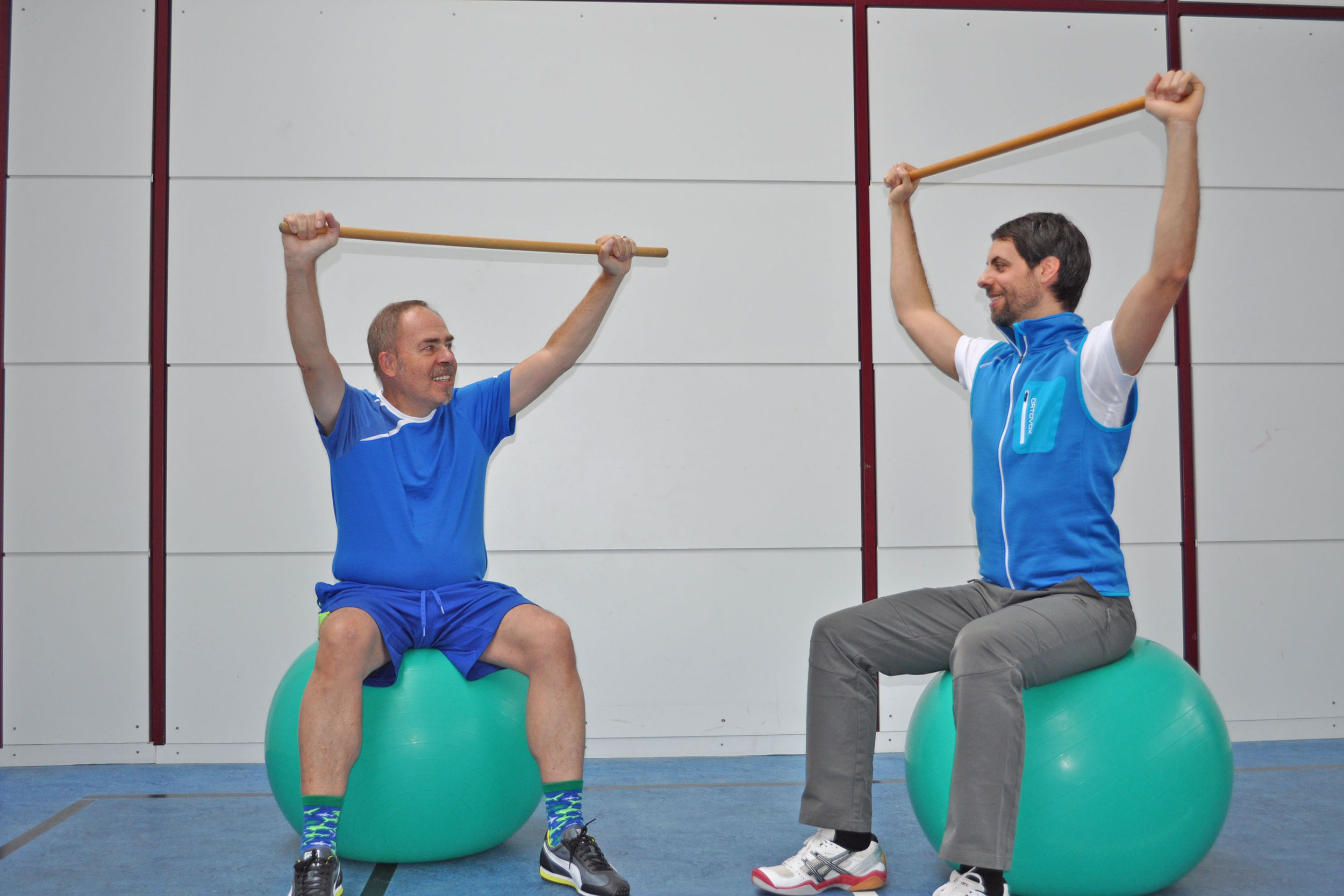 Übungsleiter Dr. Heiko Gaßner (rechts) zeigt den Teilnehmern des Rehabilitationsprogramms, wie sie mit unterschiedlichen Hilfsmitteln gleichzeitig ihre Koordination und die Muskeln stärken können. (Bild: Uniklinikum Erlangen)