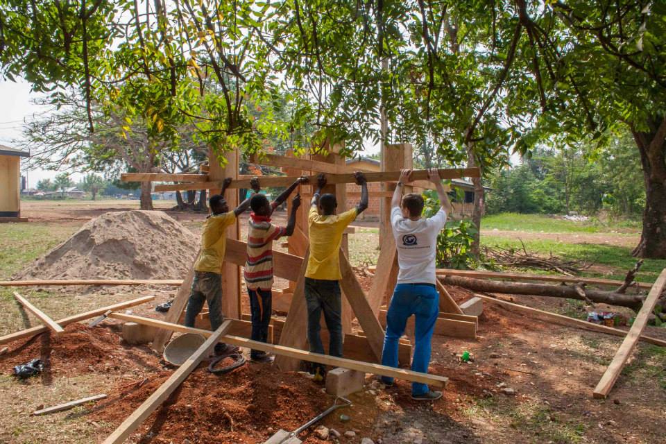Florian und drei Ghanaer bauen an einer Holzkonstruktion.