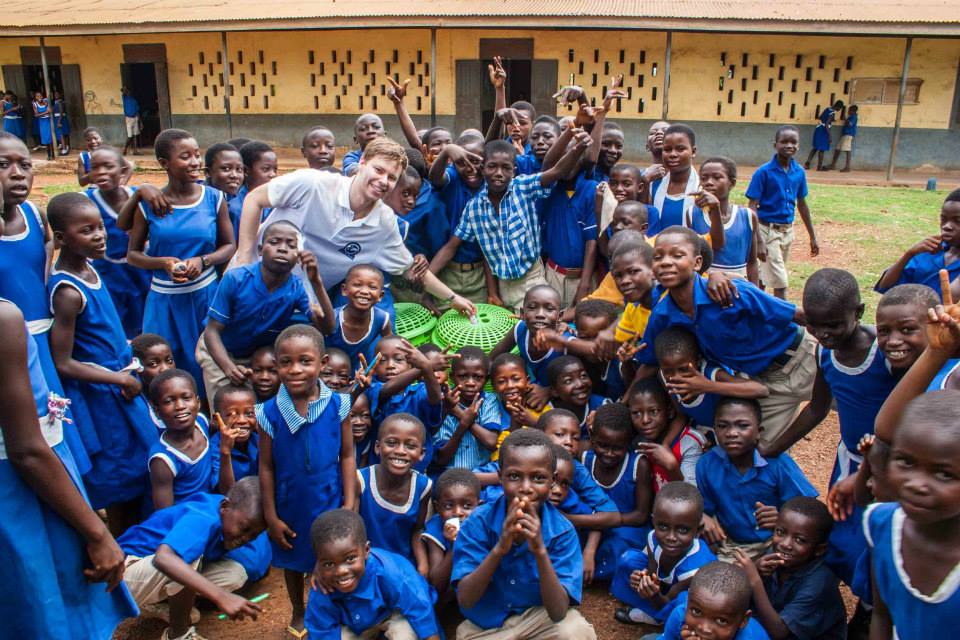 Florian bei der Übergabe von Müllbehältern an eine ghanaische Grundschule. Er steht in der Mitte, um ihn herum die Schüler.