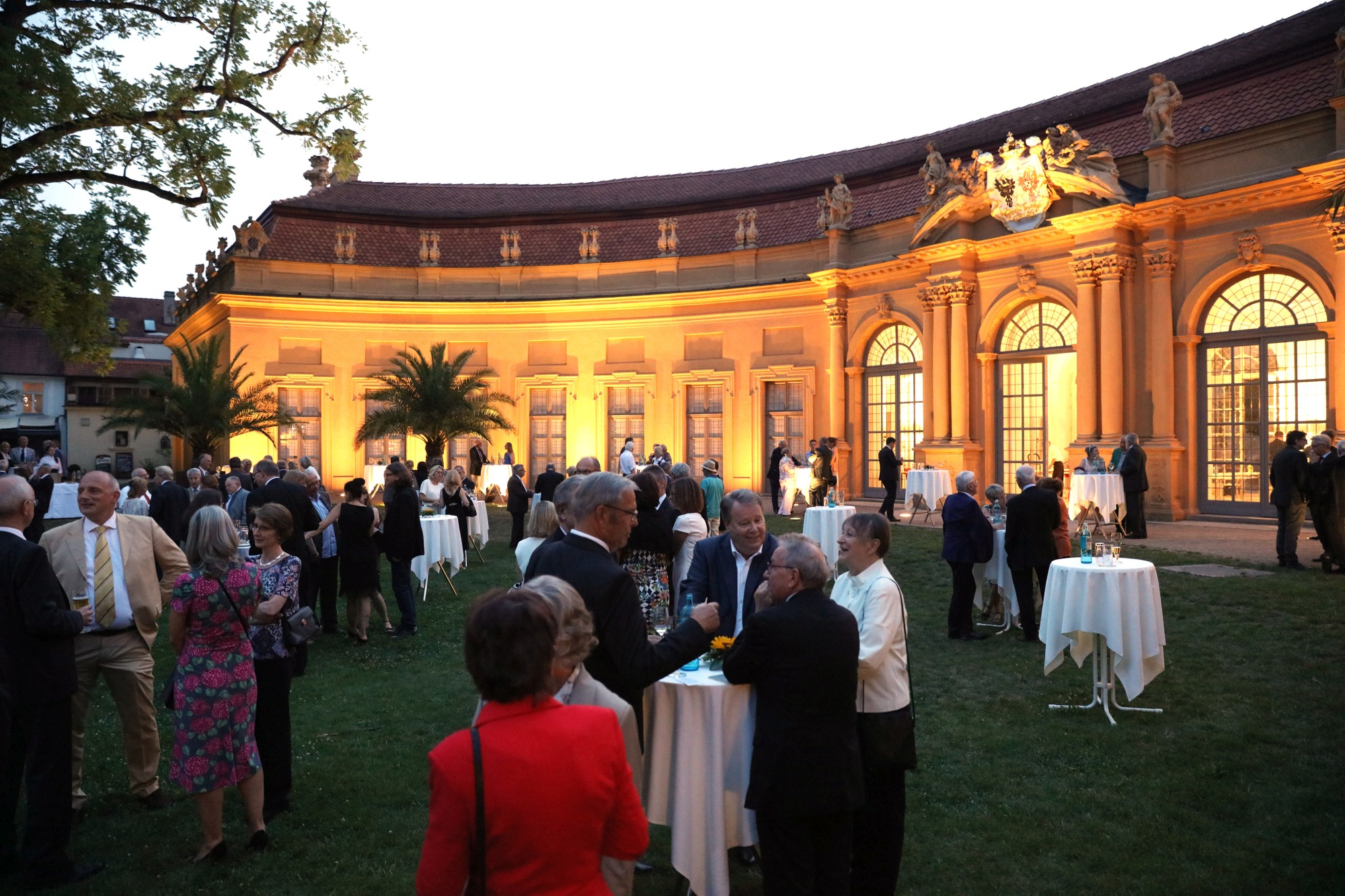Eine Menschentraube vor der Orangerie. Die Orangerie ist stark von der Sonne beleuchtet.