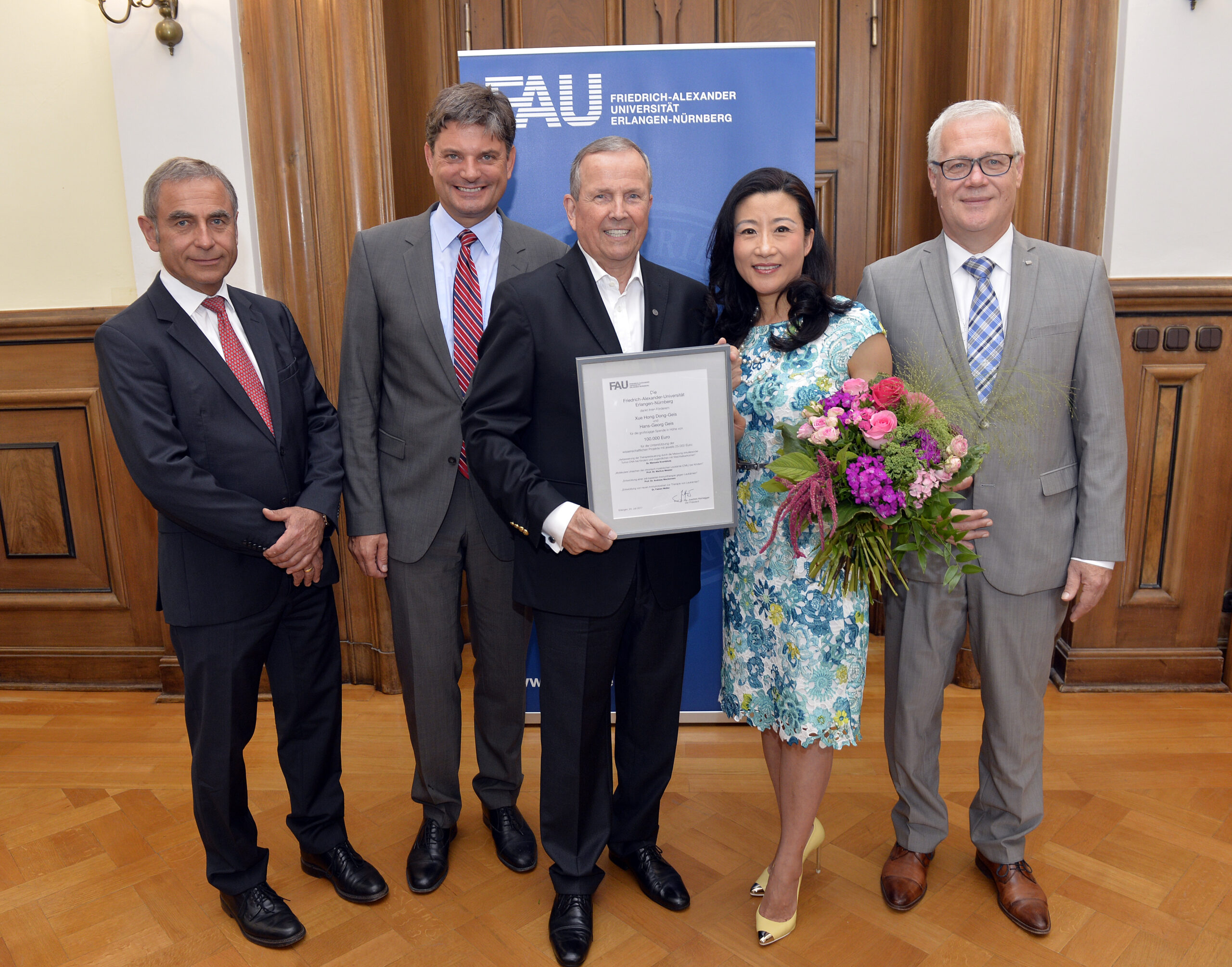 Der Unternehmer Hans-Georg Geis und seine Frau Xue Hong Dong-Geis fördern die Krebsforschung an der FAU mit einer Spende von 100000 Euro für vier Projekte. Alle Beteiligten kamen zur Übergabe der Förderurkunde ins Amtszimmer des FAU-Präsidenten Joachim Hornegger. Foto (v.li): Johannes Söllner, Joachim Hornegger, Hans-Georg Geis, Xue Hong Dong-Geis und Kanzler Christian Zens. (Foto:FAU/Harald Sippel)