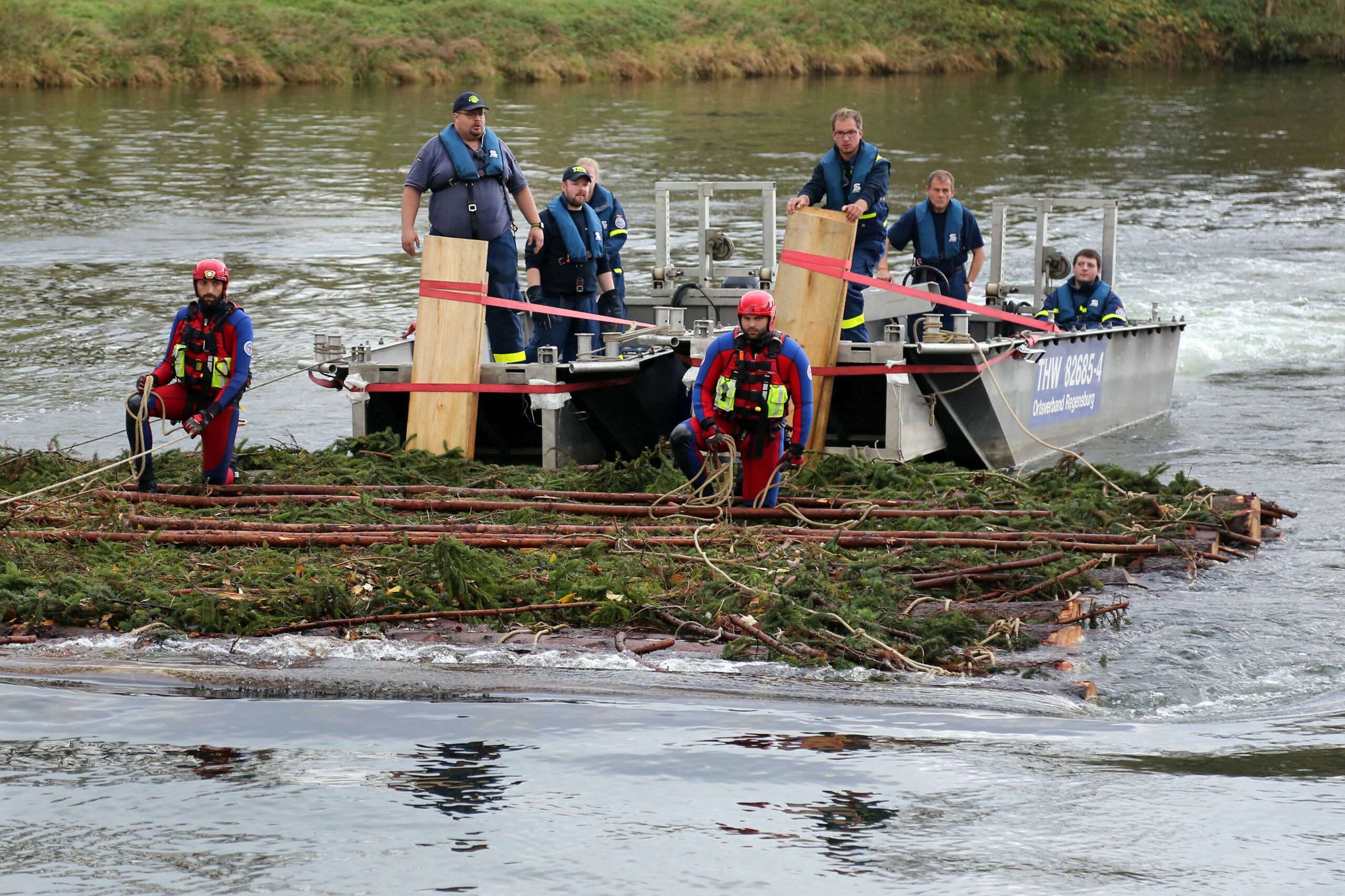 Die Wasserrettung, die bei dem Experiment half, schiebt mit einem Boot das Floß an und setzt es zurück über die Donau, wo das Experiment stattfand. (Bild: FAU/Matthias Orgeldinger)