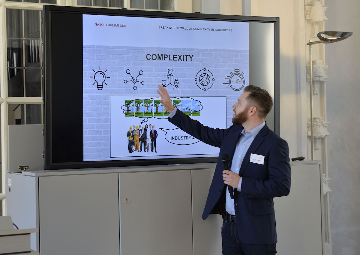Sascha Julian Oks deutet auf seine PowerPoint-Präsentation.